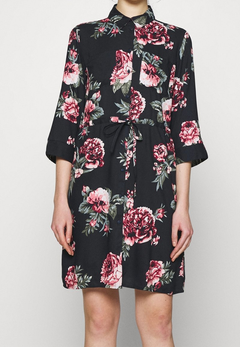 Abito nero floreale con motivi di peonie rosa e verdi, colletto, chiusura a bottoni frontale e vita regolabile con fiocco. Realizzato in tessuto leggero, maniche a 3/4.