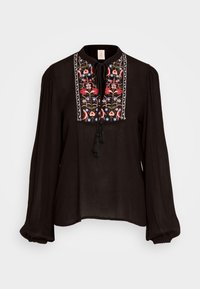 Svart blus med långa ärmar, prydd med färgglad blomsterbroderi på oket och knytdetalj. Tillverkad av lätt tyg med en mjuk textur.