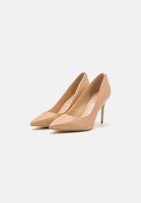 Beige high-heeled pumps featuring a pointed toe design, smooth leather material, and a sleek silhouette. Stiletto heel accentuates height.