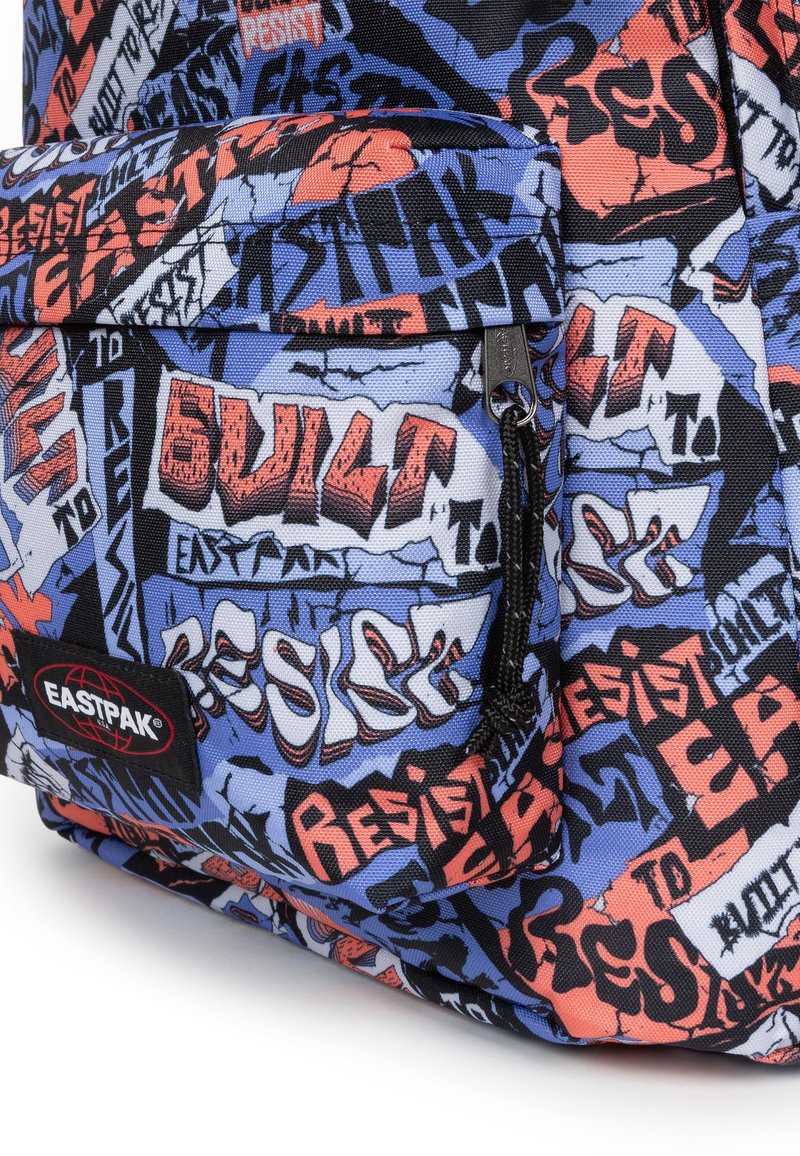 Le sac à dos Eastpak multicolore présente une base en tissu bleu avec du texte de style graffiti en rouge et noir, des zips et une poche avant.