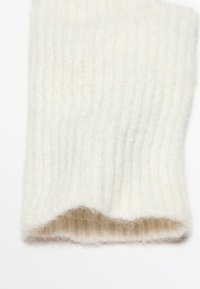 Scaldamuscole bianchi in maglia con texture a costine, realizzati in un tessuto morbido, con un bordo leggermente arricciato all'apertura.