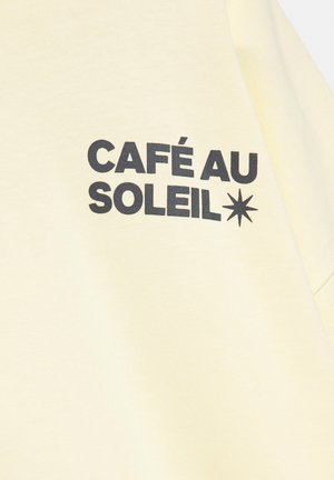 Material galben deschis cu text negru îngroșat „CAFÉ AU SOLEIL” și un simbol negru de stea cu opt colțuri în partea dreaptă.