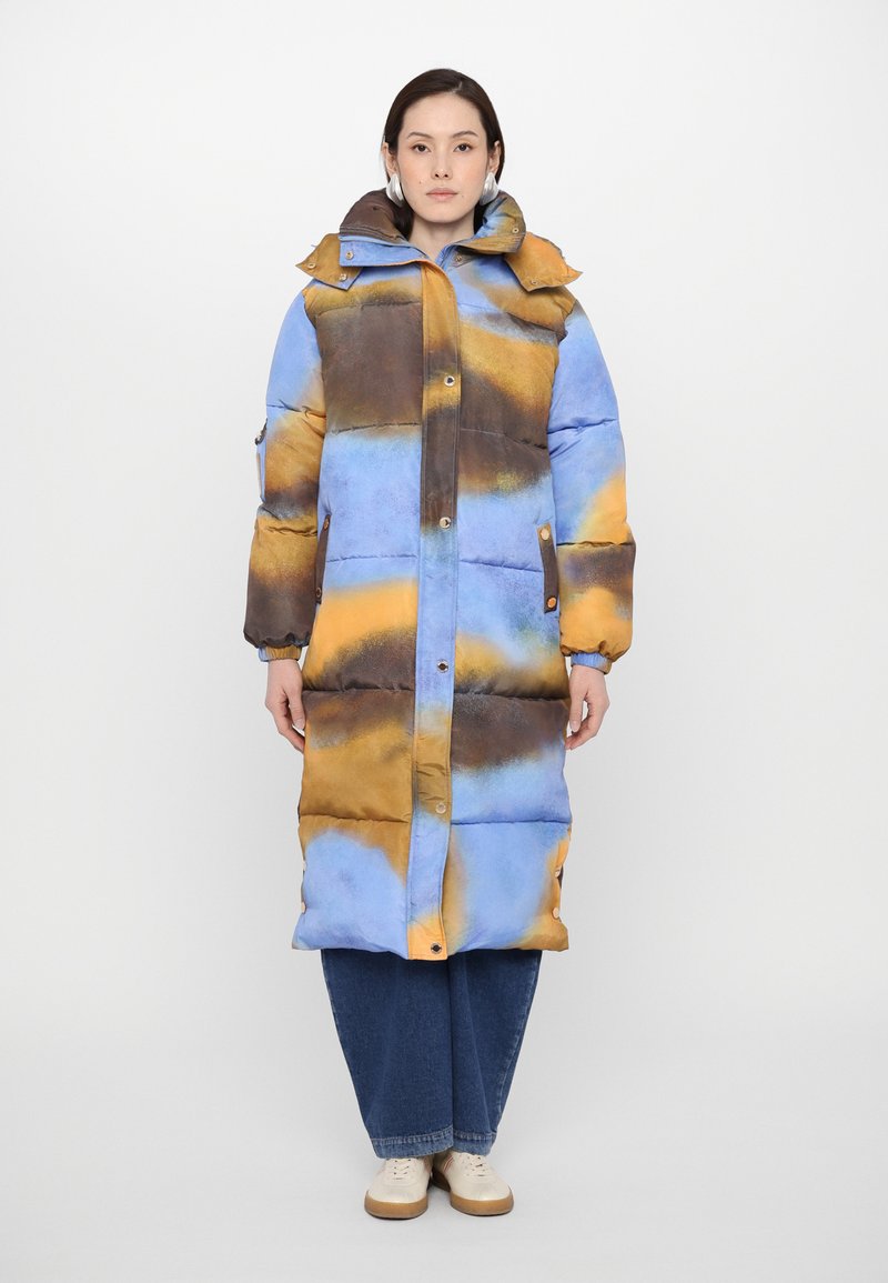Langer gefütterter Mantel mit einem blauen, braunen und orangefarbenen abstrakten Muster. Ausgestattet mit einem hohen Kragen, Knopf- und Druckknopfverschlüssen sowie Seitentaschen.