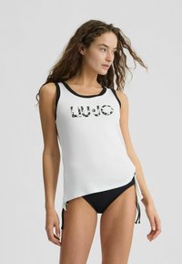 Débardeur blanc avec des accents noirs, arborant "LIU.JO" en sequins. Accompagné d'un bas de bikini noir, présentant un design sportif et élégant.