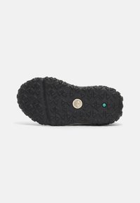 Suela de zapato negra con un patrón de dibujo texturizado, que presenta un logo circular y acentos de color, diseñada para mejorar el agarre y la durabilidad.