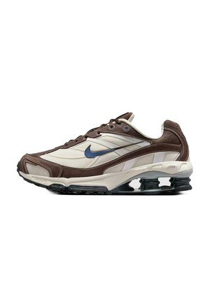 Zapatilla deportiva marrón y crema con el swoosh azul de Nike, soportes de suela negra en forma de resorte y entresuela blanca.