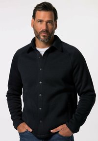 Veste à boutonner bleu marine foncé, en tissu côtelé. Dotée d'un col, de boutons noirs et de poches latérales. Design ajusté.