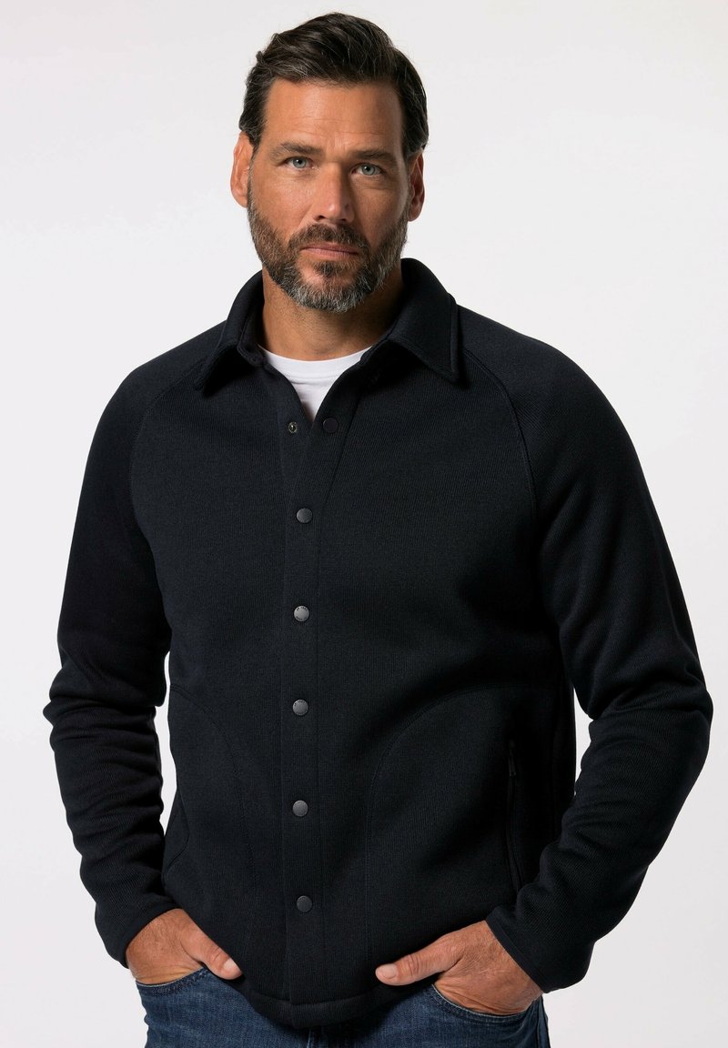 Veste à boutonner bleu marine foncé, en tissu côtelé. Dotée d'un col, de boutons noirs et de poches latérales. Design ajusté.