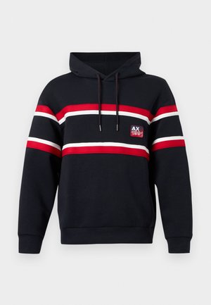 Mornarska dukserica s horizontalnim crvenim, bijelim i crnim prugama. Ima prednji džep, kapuljaču sa vezicom i zakrpu s logom na prsima.