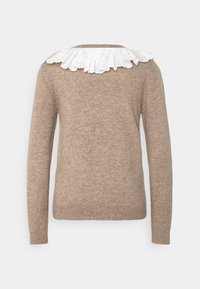 Pull beige à manches longues en tricot avec un col en dentelle blanche à volants sur un fond uni.