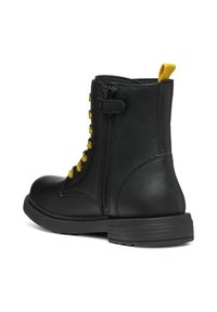 Stivale alla caviglia in pelle nera con lacci gialli, cerniera laterale, punta arrotondata e suola testurizzata. Presenta una piccola linguetta sul retro.
