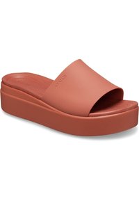 Sandale à plateforme en matériau flexible de couleur corail, avec une large sangle sur le dessus et une semelle intérieure texturée pour un confort optimal.