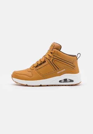 Hög-top sneakers i senapsgul läder med vita inslag, texturerad yta och en synlig luftkuddenhet i sulan.
