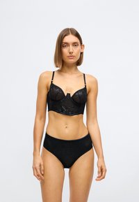 Zwarte lingerieset met een sheer, gestructureerde bh en hoog gewaisted slipjes, versierd met kleine pailletten en zwarte bies.