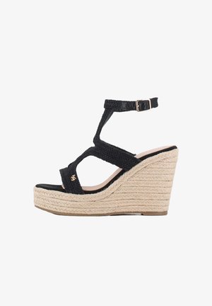 Sandalias de cuña tejidas en negro con plataforma elevada, tira ajustable en el tobillo y tacón envuelto en yute. Suela negra lisa y detalle en oro.