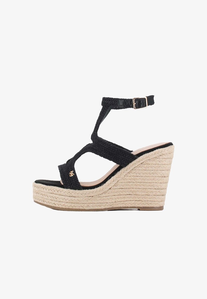 Sandalias de cuña tejidas en negro con plataforma elevada, tira ajustable en el tobillo y tacón envuelto en yute. Suela negra lisa y detalle en oro.