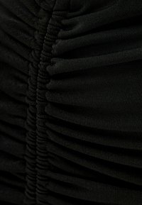 Tissu noir avec fronces horizontales, présentant une texture plissée et une finition lisse, mettant en valeur le design structuré et la flexibilité.