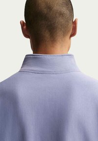 Pull-over violet clair avec un col à col, une texture lisse et un détail de surpiqûres visible sur le col. Vue de dos montrant des cheveux courts.