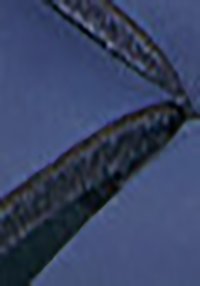 Sininen kangas, jossa on teksturoitu pinta, esittää kahta päällekkäistä kolmiomaista muotoa. Reunat ovat hienosti ommeltuja, mikä korostaa suunnittelun yksityiskohtia.