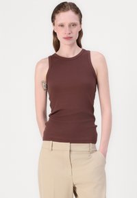 Bruine mouwloze tanktop in een aansluitend ontwerp, gemaakt van een glad materiaal, gecombineerd met lichtbeige broek. Eenvoudige halslijn zonder versieringen.