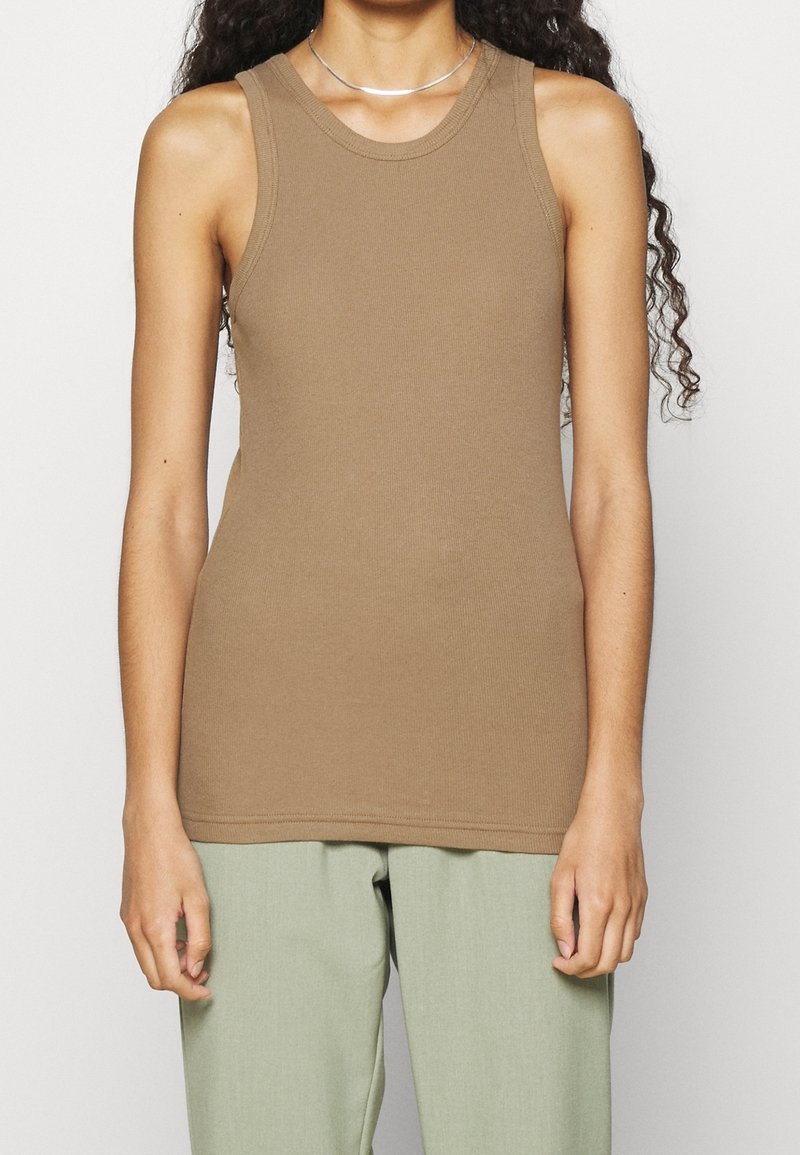 Top sin mangas ajustado de color marrón, con textura acanalada, escote redondo, combinado con pantalones de color verde claro. Diseño simple, sin patrones ni acentos visibles.