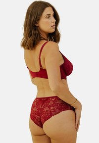 Ensemble de soutien-gorge et culottes en dentelle cramoisie avec motifs floraux, bretelles ajustables et ourlet festonné. Texture douce avec des détails fins.