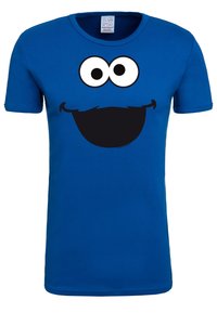 Blue cotton t-shirt featuring a large black smile, big white eyes, and a mustache graphic on the front. Short sleeves and crew neck design.