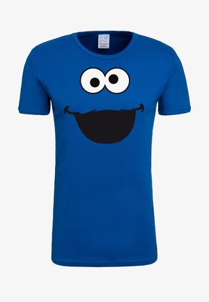 Blue cotton t-shirt featuring a large black smile, big white eyes, and a mustache graphic on the front. Short sleeves and crew neck design.