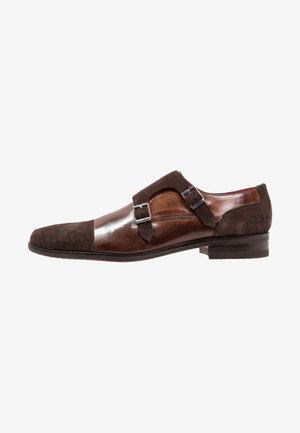 Zapato de cuero marrón con acentos de gamuza, cierre de doble hebilla, punta afilada y diseño elegante. Superficie suave y texturizada. Suela negra.