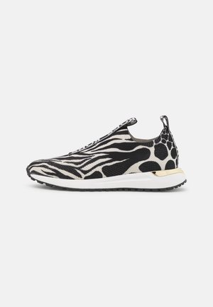 Baskets slip-on avec tige en maille imprimée animal noir et blanc, semelle blanche, semelle extérieure noire et accent doré sur le talon.