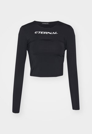 Musthave musta pikkade varrukatega lühike topp, valmistatud siledast kangast, millel on rinna kohal sõna "IGAVIKU" hõbedaselt ja horisontaalne lõike detail.