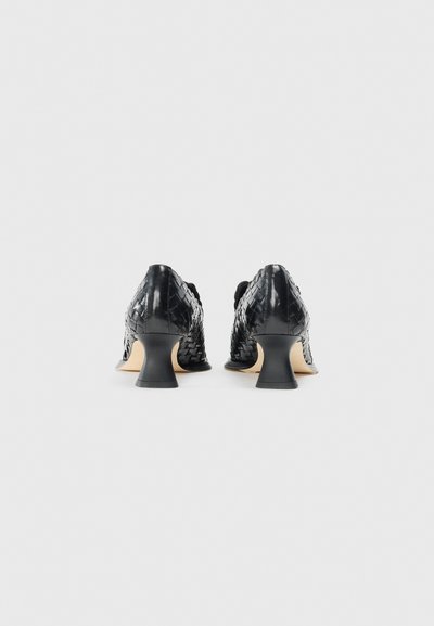 Scarpe con tacco nere dal design intrecciato, con una superficie testurizzata e un tacco spesso in contrasto. L'interno è beige.
