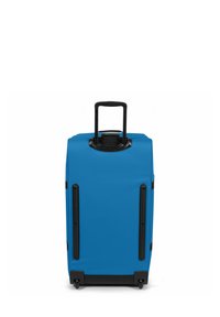 Valigia blu con design robusto a guscio rigido. Presenta un manico estendibile, quattro ruote nere e una superficie testurizzata.