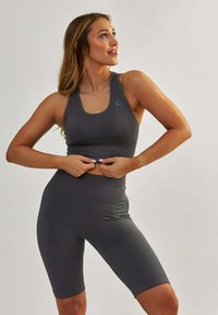 Ciemnoszary prążkowany krótki top sportowy i dopasowane, wysokie spodenki rowerowe, z delikatnym logo i dopasowanym krojem.