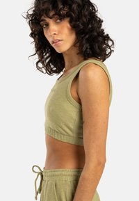 Oliven grønn cropped tanktop laget av strukturert stoff, med brede armhull og en tettsittende silhuett, kombinert med matchende joggebukser med snøring.