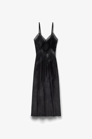 Zwarte jurk met dunne bandjes, gemaakt van zachte stof. Voorzien van kantaccenten en een diamantvormig patroon op het bovenstuk. Soepele, lange rok.