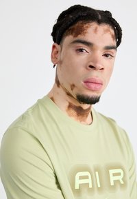 Λαμπερό πράσινο κοντομάνικο μπλουζάκι με μεγάλο λογότυπο "AIR" σε κίτρινο-πράσινο χρώμα, με μαλακή βαμβακερή υφή.