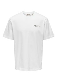 T-shirt en coton blanc à manches courtes et col rond. Présente un texte imprimé en noir "PARIS BAKERY" et "Pain frais quotidien."