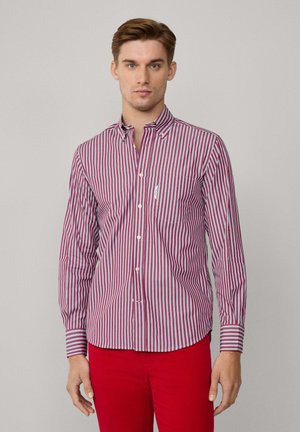 Camisa de botones a rayas rojas y blancas con cuello, mangas largas y un bolsillo en el pecho, hecha de una tela ligera.