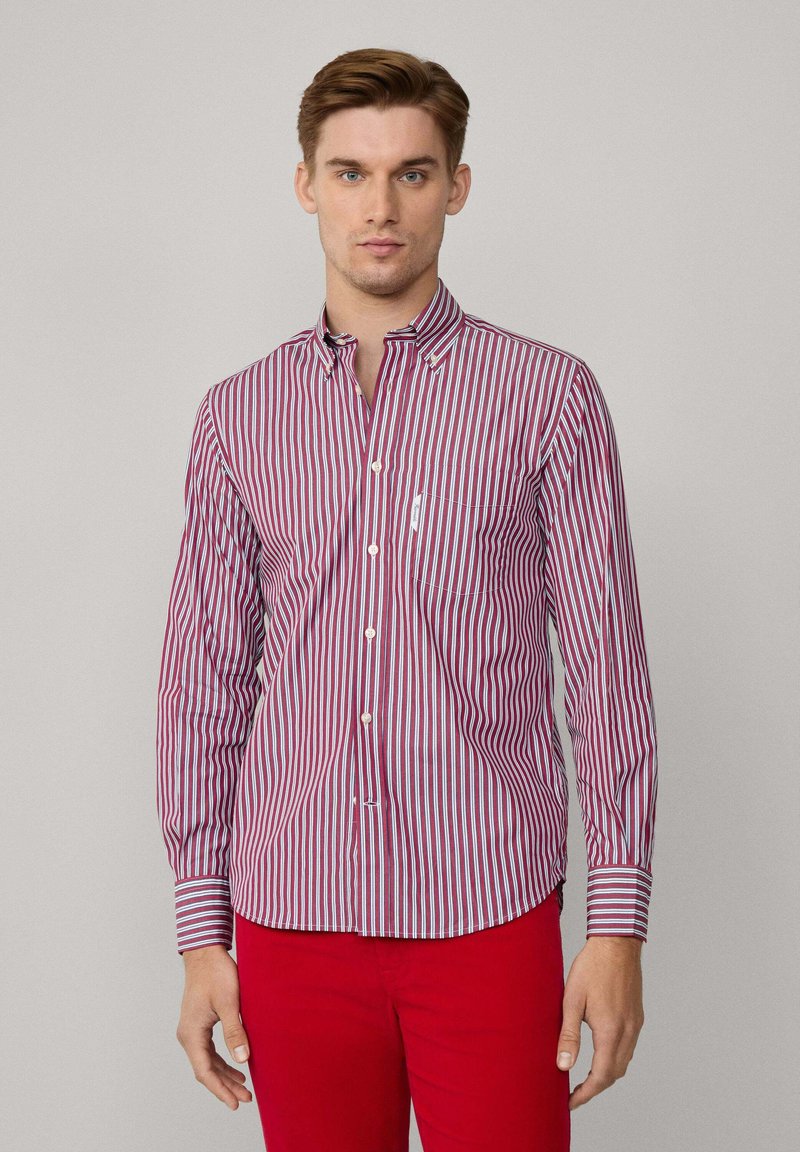 Camisa de botones a rayas rojas y blancas con cuello, mangas largas y un bolsillo en el pecho, hecha de una tela ligera.