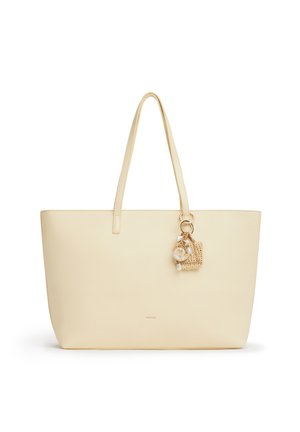 Borsa tote in pelle color crema con sottili spalline e un piccolo ciondolo decorativo intrecciato con conchiglie attaccate.