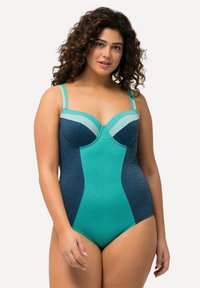 Maillot de bain une pièce avec un mélange de couleurs bleu canard et bleu marine, tissu texturé, bustier structuré avec armatures et bretelles ajustables.