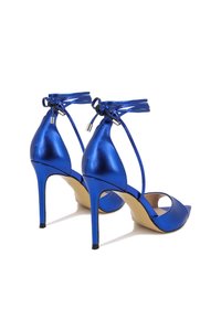 Scarpe col tacco alto in metallo blu, con punta affusolata e lacci alla caviglia, caratterizzate da una texture liscia e un design con tacco sottile.