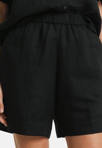 Zwarte linnen shorts met een elastische tailleband, met een relaxed fit, een gladde textuur en zijnaden die subtiele details toevoegen.