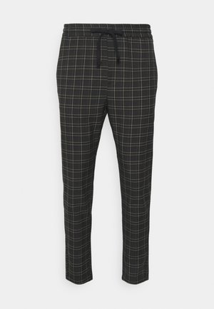 Schwarze Hose mit weißem Karomuster, elastischem Bund und schwarzem Kordelzug, zulaufende Beine, auf weißem Hintergrund dargestellt.