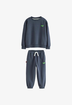 Marineblåt sæt med sweatshirt og joggers med neongrønt logo, elastiske manchetter og hvid snor i joggerens taljebånd.