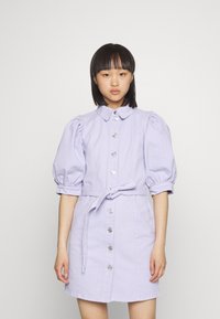 Vestido de ganga lilás com mangas curtas em balão, gola, fecho frontal com botões e cintura com cinto para um visual ajustado.