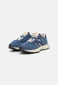 Zapatillas de correr azules con tejido texturizado, cordones blancos y suela de goma negra. Presenta un logo naranja en la lengüeta y acentos reflectantes.