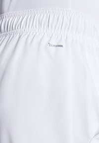 Pantaloni sportivi bianchi caratterizzati da un tessuto testurizzato, cintura elastica e marchio "ClimaCool". Design liscio e leggero.