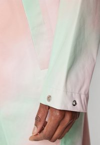 Pastell gradient skjorte med rosa til grønn nyanser, knappe mansjett, laget av lett stoff, med en glatt tekstur og skarpe linjer.